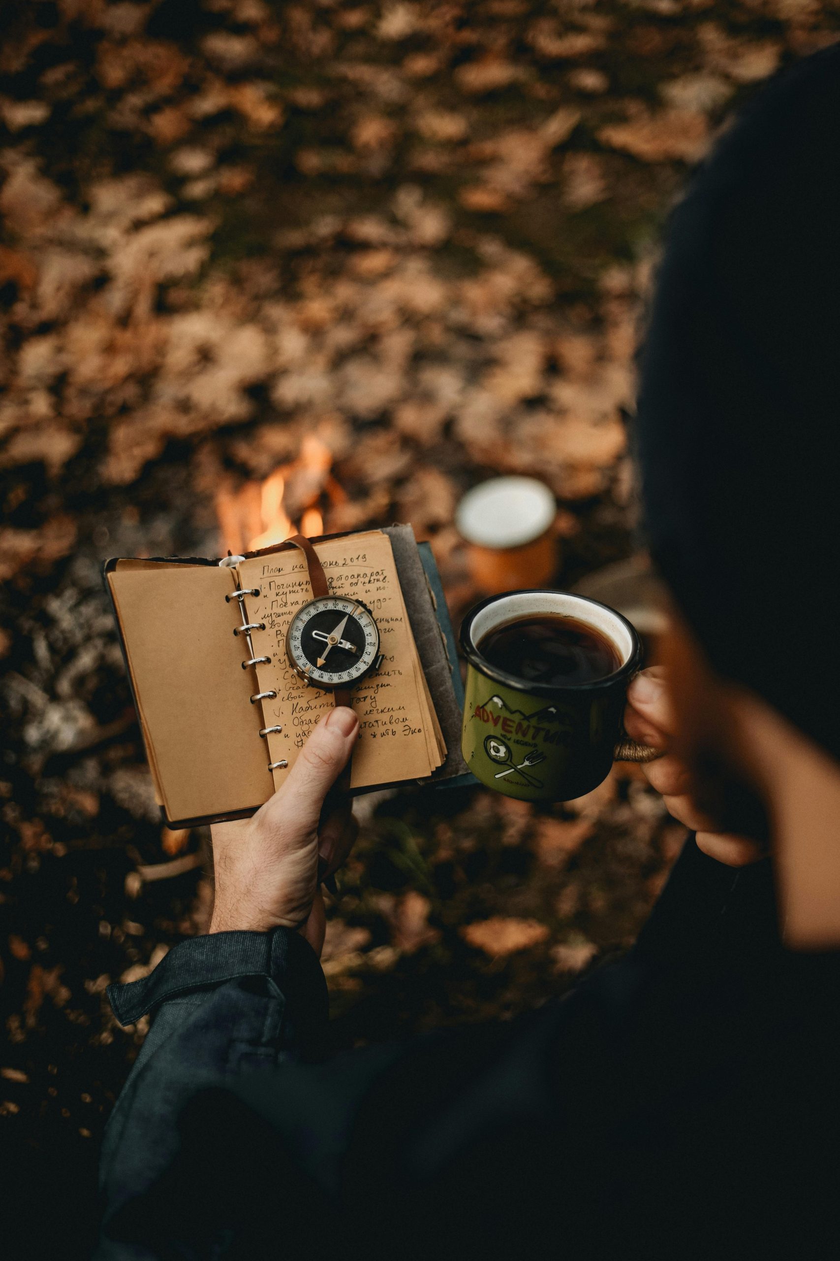 bussola-article man reading his diaries with a compass over it and a mug of coffee